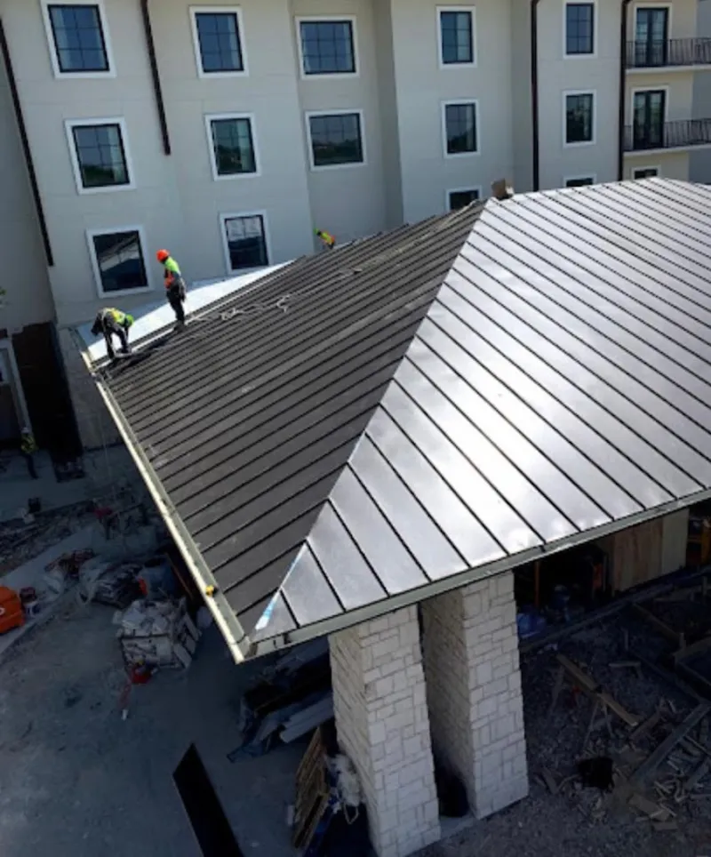 Crew installing standing seam metal roof panels on a commercial project in Sunland Park
